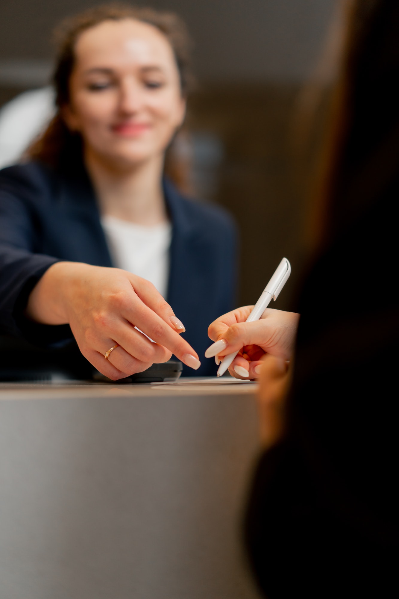 close-up of a smiling receptionist helping a guest to fill out a registration form at the hotel