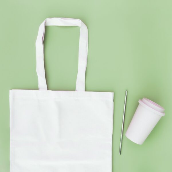 Eco paper bag flat lay on green background