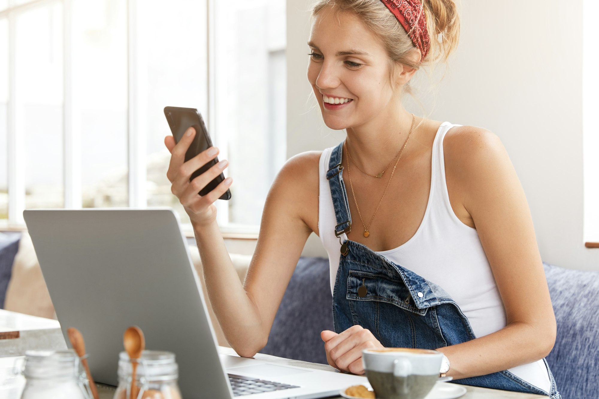 Lovely female checks her bank account on mobile phone application, satisfied to recieve money reward